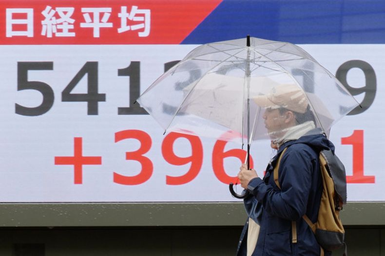 Unas personas caminan frente a un panel electrónico que muestra las cotizaciones del índice Nikkei de Japón, el jueves 2 de abril de 2026, en Tokio. (Foto AP/Eugene Hoshiko)