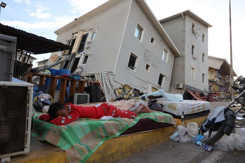 Un niño duerme en la calle ante casas dañadas por los sismos en Catia La Mar, Venezuela, el domingo 28 de junio de 2026. (AP Foto/Pedro Mattey)