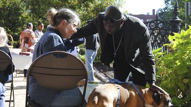 El reverendo Jean Beniste, un inmigrante haitiano, bendice a un perro y a su propietaria, el sábado 5 de octubre de 2024, durante el evento de Bendición de Animales en el jardín de la Iglesia Episcopal St. Paul de Concord, Nueva Hampshire. (G. Jeffrey MacDonald vía AP)