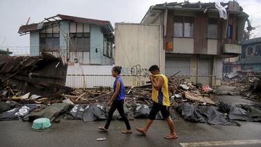 americateve | Dos personas pasan junto a cad&aacute;veres de las v&iacute;ctimas del tif&oacute;n Haiyan, el s&aacute;bado 16 de noviembre del 2013, en la ciudad de Taclob&aacute;n, en el centro de las Filipinas. (Foto AP/Wong Maye-E)