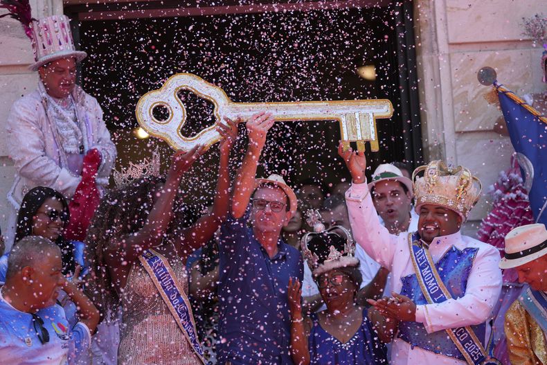 El rey Momo, Kaio Mackenzie, derecha, con la reina Thuane de Oliveira, reciben las llaves de la ciudad del alcalde Eduardo Paes, centro, en la ceremonia que de inicio oficialmente al carnaval en Río de Janeiro, Brasil, el viernes 28 de febrero de 2025. (AP Foto/Silvia Izquierdo)