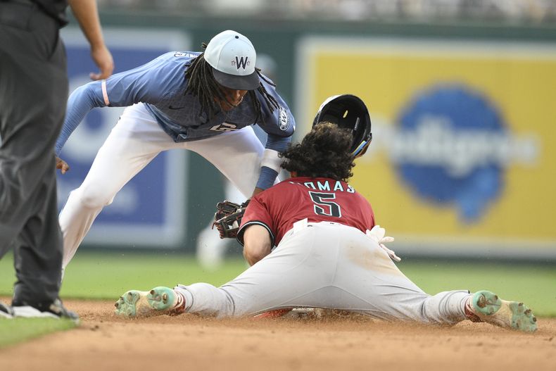 Alek Thomas, de los Diamondbacks de Arizona, a la derecha, intenta robar la segunda base contra el campocorto de los Nacionales de Washington, CJ Abrams, segundo desde la derecha, durante la novena entrada de un juego de béisbol en una jugada que fue impugnada por los Diamondbacks pero que se mantuvo como un out, el sábado 5 de abril de 2025, en Washington. (AP Foto/Nick Wass)