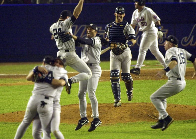 ARCHIVO - El primera base de los Yankees de Nueva York, Tino Martínez (24), salta a los brazos del lanzador Mariano Rivera mientras el receptor Jorge Posada, tercero desde la derecha, Scott Brosius (18) y otros celebran después de derrotar a los Mets de Nueva York en el Juego 5 de la Serie Mundial 4-2 para convertirse en los campeones de la Serie Mundial de 2000, el 26 de octubre de 2000, en el Shea Stadium de Nueva York. (AP Foto/Bill Kostroun, archivo)