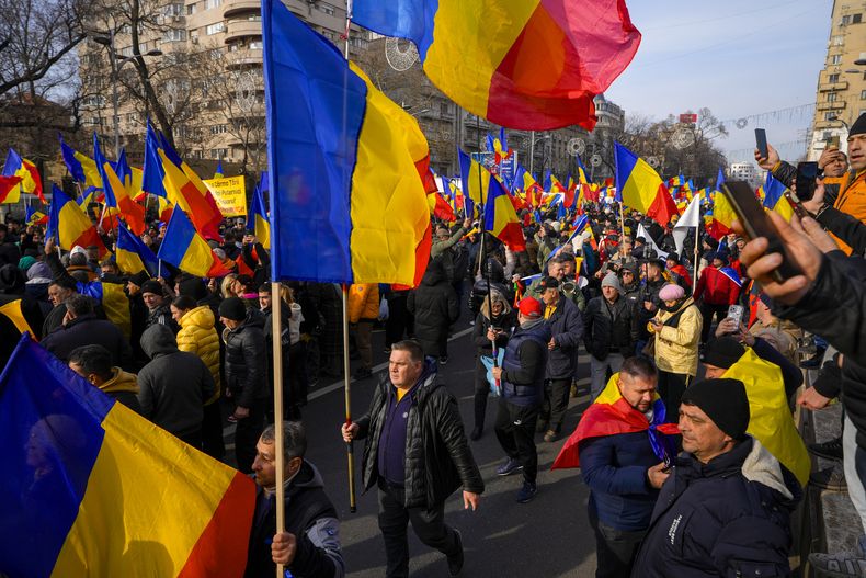 Manifestantes ondean banderas de Rumania durante una marcha organizada por la derechista Alianza por la Unidad de los Rumanos, para exigir elecciones libres después de que la Corte Constitucional de Rumania anuló la primera vuelta de los comicios presidenciales de diciembre pasado, el domingo 12 de enero de 2025, en Bucarest, Rumania. (AP Foto/Vadim Ghirda)