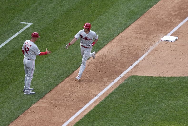 J.T. Realmuto, de los Filis de Filadelfia, recorre las bases junto al coach de la antesala Dusty Wathan, tras conectar un jonrón en el juego del sábado 3 de junio de 2023, ante los Nacionales de Washington (AP Foto/Patrick Semansky)