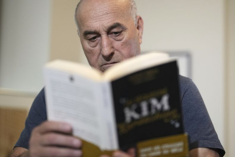 Yunice Abbas, uno de los hombres acusados del robo a mano armada de Kim Kardashian en 2016, lee el libro Jai séquestré Kim Kardashian durante una entrevista con Associated Press, el martes 22 de abril de 2025 en París. (Foto AP/Thibault Camus)
