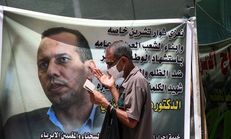 Un hombre hace oración en Bagdad el 12 de julio de 2020 frente a un cartel con la imagen de Hisham al-Hashimi, un analista iraquí que fue asesinado. (Foto AP/Khalid Mohammed)