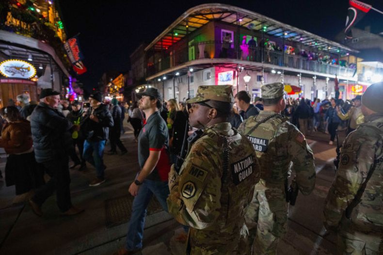 ARCHIVO – La Guardia Nacional y otros miembros uniformados de los organismos de seguridad pública de agencias federales, estatales y locales patrullan mientras un grupo de personas que celebran recorren Bourbon Street en Nueva Orleans, el 31 de diciembre de 2025. (AP Foto/Matthew Hinton, Archivo)