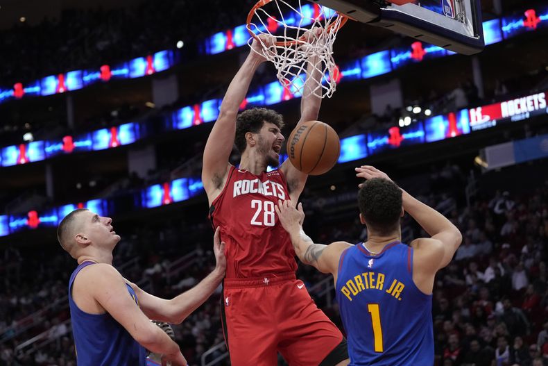 Alperen Sengun (28), de los Rockets de Houston, clava el balón en la canasta, mientras Michael Porter Jr. (1) y Nikola Jokic, de los Nuggets de Denver, defienden durante la segunda mirad del juego de baloncesto de la NBA, el domingo 12 de noviembre de 2023, en Houston. Los Rockets ganaron 107-104. (AP Foto/David J. Phillip)