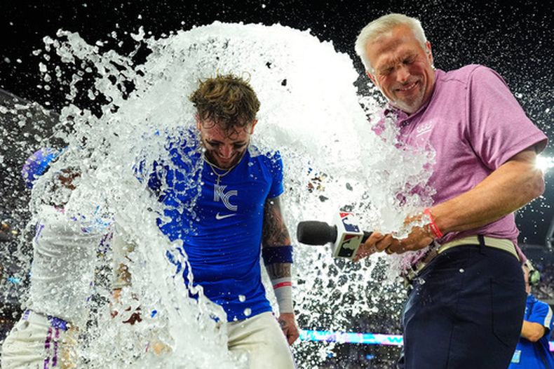Carter Jensen, de los Reales de Kansas City, junto al comentarista Joel Goldberg, son empapados por sus compañeros después de su partido de béisbol, el viernes 17 de julio de 2026, en Kansas City, Misuri. (Foto AP/Charlie Riedel)