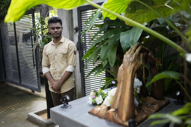 Jayarasa Abilash, conocido como Baby 81 por haber sido arrastrado por el tsunami del Océano Índico de 2004, frente a un monumento construido en memoria de las víctimas del tsunami frente a su residencia en Kurukkalmadam, Sri Lanka, martes 17 de diciembre de 2024. (AP foto/Eranga Jayawardena)
