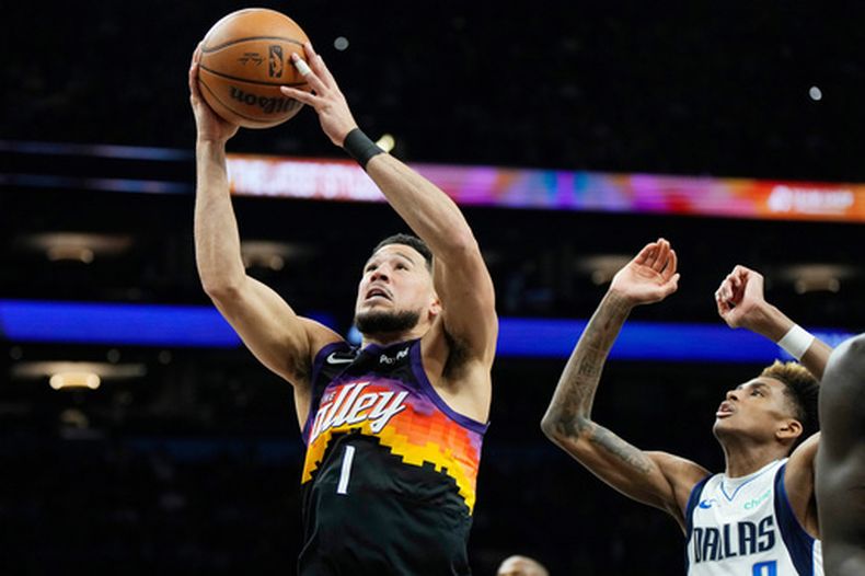 Devin Booker, base de los Suns de Phoenix, elude a AJ Johnson, de los Mavericks de Dallas, en el partido del miércoles 8 de abril de 2026 (AP Foto/Ross D. Franklin)