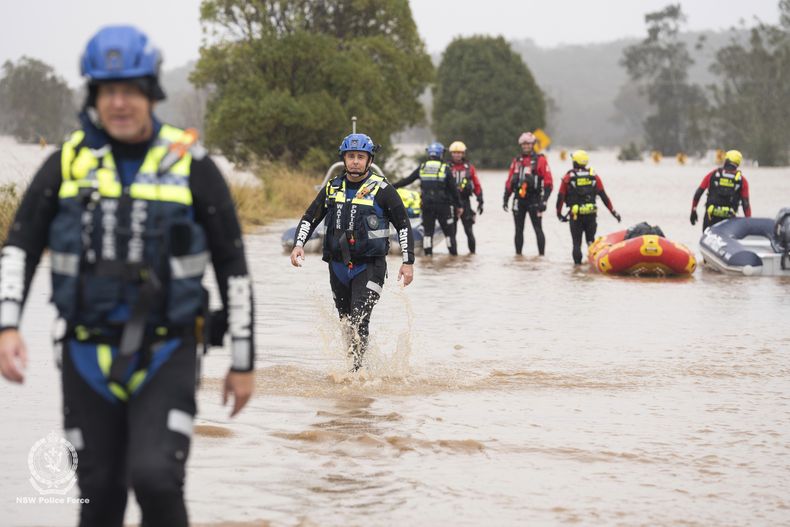 En esta foto suministrada por la policía de Nueva Gales del Sur, socorristas vadean una inundación mientras preparan botes inflables cerca de Taree, Australia, el jueves 22 de mayo de 2025. (Policía de Nueva Gales de Sur vía AP)
