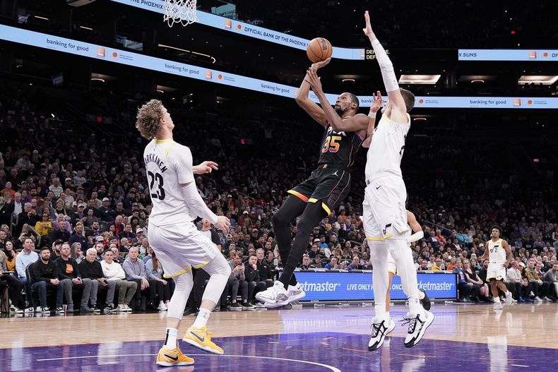 Kevin Durant, de los Suns de Phoenix, dispara entre Laury Markkanen (izquierda) y Walker Kessler, del Jazz de Utah, el jueves 8 de enero de 2024 (AP Foto/Darryl Webb)