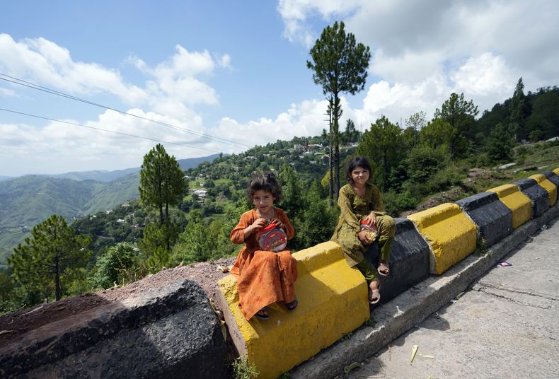 Dos niñas que venden dulces posan para una fotografía el domingo 9 de julio de 2023, en Murree, Pakistán. (AP Foto/Rahmat Gul)
