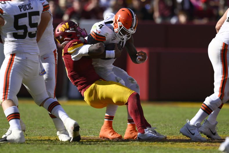 Deshaun Watson (4), quarterback de los Browns de Cleveland, es capturado detrás de la línea de golpeo por Dante Fowler Jr. (6), de los Commanders de Washington, durante la segunda mitad del juego de la NFL, en Landover, Maryland, el domingo 6 de octubre de 2024. (AP Foto/Nick Wass)