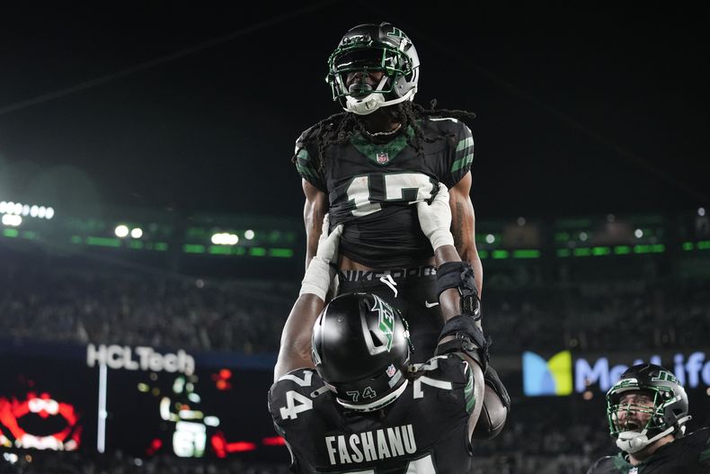 Olu Fashanu, de los Jets de Nueva York, carga al receptor Davante Adams, luego de un touchdown ante los Texans de Houston, el jueves 31 de octubre de 2024 (AP Foto/Frank Franklin II)
