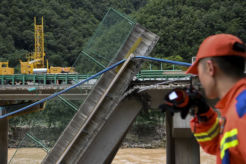 En esta imagen distribuida por la agencia noticiosa Xinhua, un rescatista observa un puente derrumbado durante una operación de búsqueda y rescate en un río en el condado de Zhashui, en la ciudad de Shangluo, en la provincia noroccidental china de Shaanxi, el 20 de julio de 2024. (Zou Jingyi/Xinhua vía AP)
