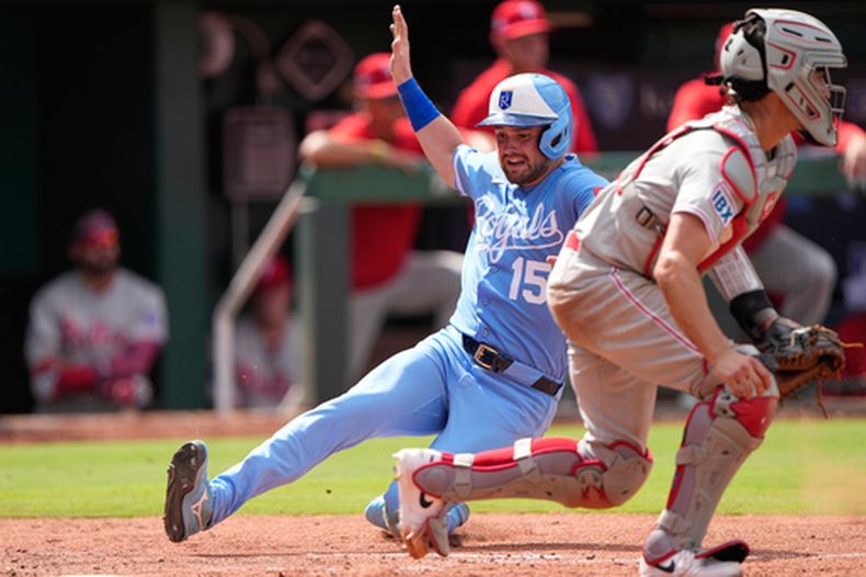 Lane Thomas (15), de los Reales de Kansas City, llega barrido al plato mientras el receptor Garrett Stubbs, de los Filis de Filadelfia, para anotar con un doble productor de dos carreras de Salvador Pérez durante la octava entrada del juego de béisbol de las Grandes Ligas, el domingo 5 de julio de 2026, en Kansas City, Missouri. (AP Foto/Charlie Riedel)
