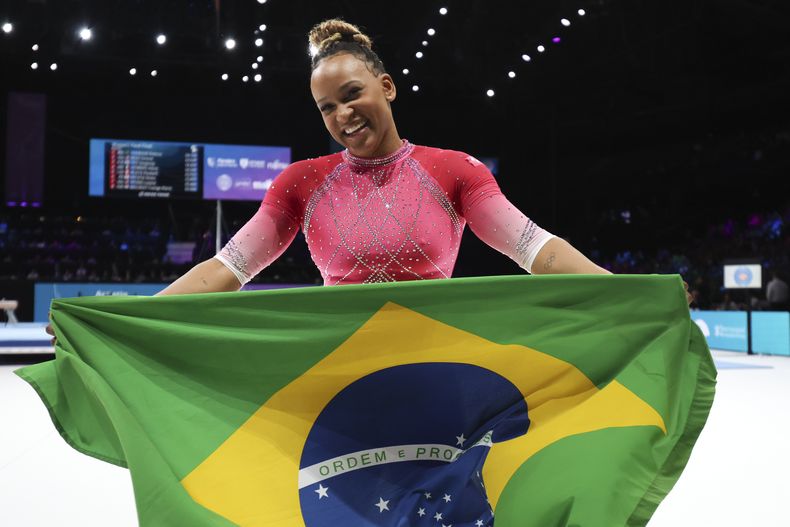 La brasileña Rebeca Andrade celebra con la bandera nacional tras ganar la medalla de oro del salto del potro en el Mundial de gimnasia artística, el sábado 7 de octubre de 2023, en Amberes. (AP Foto/Geert vanden Wijngaert)