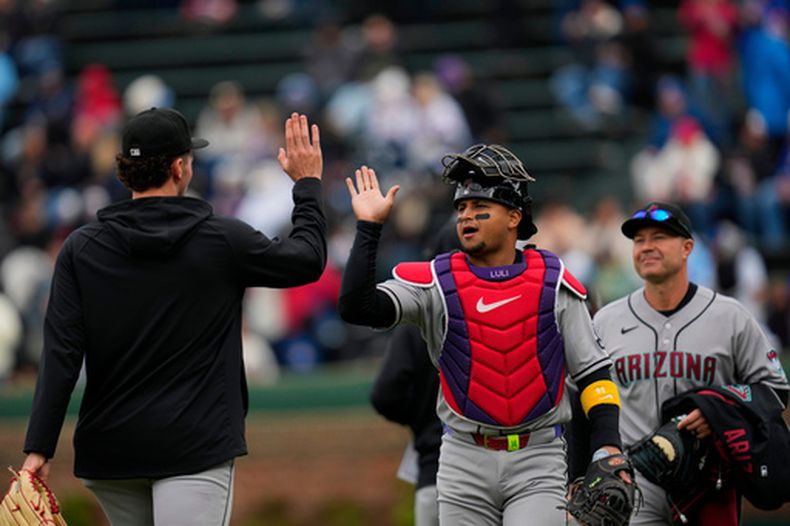 Gabriel Moreno (14), receptor de los Diamondbacks de Arizona, choca manos con un compañero antes del partido de béisbol de Grandes Ligas contra los Cachorros de Chicago, el viernes 1 de mayo de 2026, en Chicago. (AP Foto/Erin Hooley)