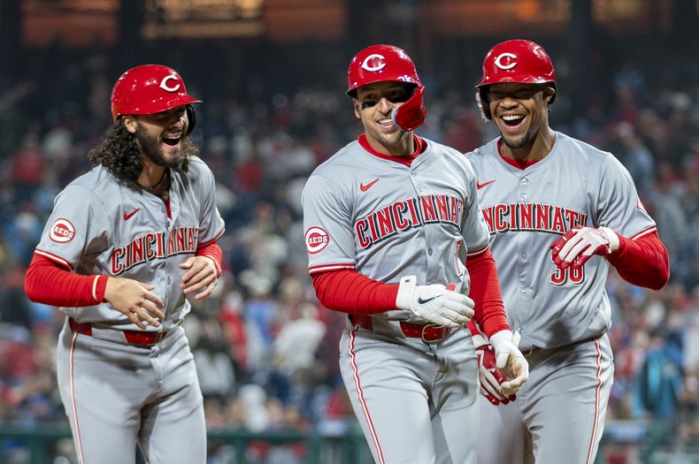 Spencer Steer, centro, de los Rojos de Cincinnati, celebra su grand slam con Jonathan India, izquierda, y Will Benson durante la décima entrada del juego de béisbol en contra de los Filis de Filadelfia, el lunes 1 de abril de 2024, en Filadelfia. (AP Foto/Chris Szagola)
