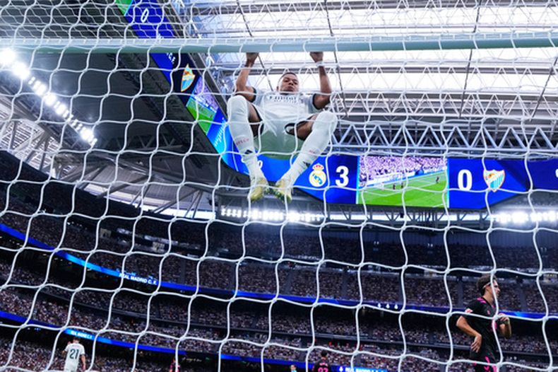 El delantero del Real Madrid Kylian Mbappé se cuelga del poste durante el partido contra Málaga en La Liga de España, el domingo 30 de agosto de 2025, en Madrid. (AP Foto/Manu Fernández)