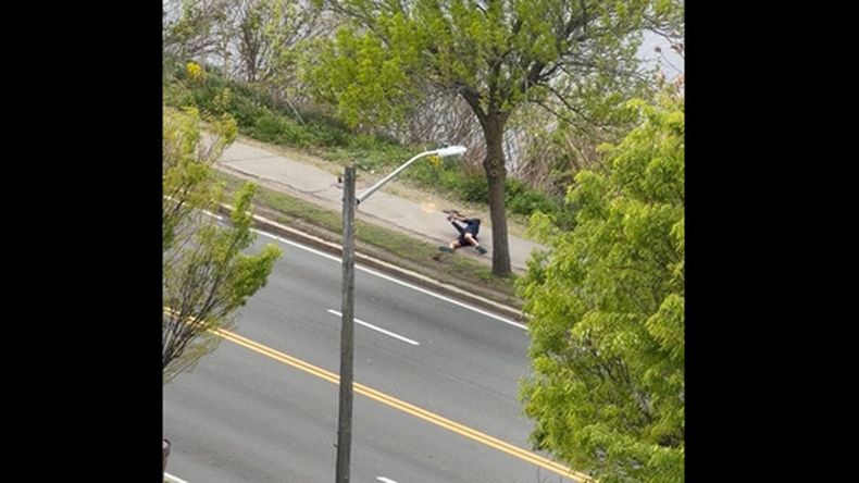 En la imagen, tomada de un video proporcionado por Youssef Adel, aparece un hombre con un rifle de asalto disparando el arma en un camino transitado en Cambridge, Massachusetts, el lunes 11 de mayo de 2026. (Youssef Adel vía AP)