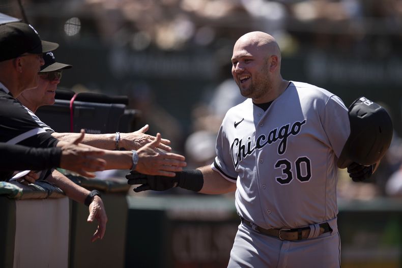 Jake Burger (30), de Medias Blancas de Chicago, es felicitado por sus compañeros de equipo después de batear cuadrangular solitario en contra de los Atléticos de Oakland durante la séptima entrada del juego de béisbol, el domingo 2 de julio de 2023, en Oakland, California. (AP Foto/D. Ross Cameron)