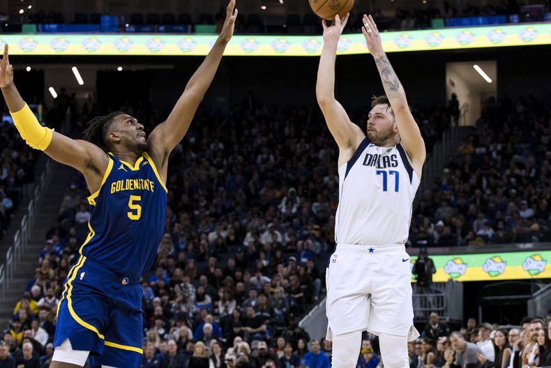 Luka Doncic, de los Mavericks de Dallas, dispara frente a Kevon Looney, pívot de los Warriors de Golden State, en el encuentro del sábado 30 de diciembre de 2023 (AP Foto/John Hefti)
