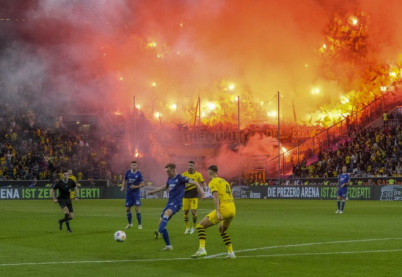 Aficionados del Dortmund encienden bengalas durante el partido entre el Hoffenheim y el Borussia Dortmund, el viernes 29 de septiembre de 2023, en Sinsheim, Alemania. (AP Foto/Michael Probst)