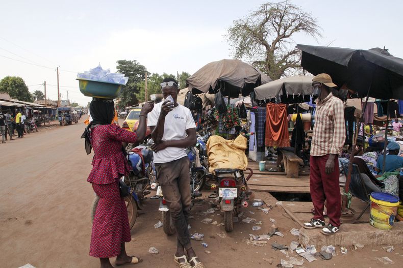 ARCHIVO - Amadou Coulibaly, conductor de mototaxi, bebe un sobre de agua para refrescarse bajo un sol abrasador en Bamako, Mali, el 18 de abril de 2024. (Foto AP/Baba Ahmed, Archivo)