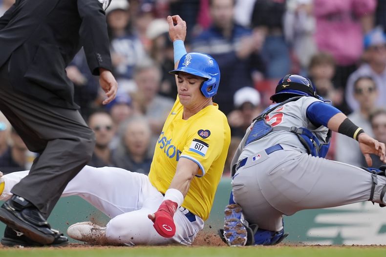 Bobby Dalbec de los Medias Rojas de Boston evita el tag del cátcher Yan Gomes de los Cachorros de Chicago tras el doble de tres carreras de Ceddanne Rafaela en la quinta entrada del juego del sábado 27 de abril del 2024. (AP Foto/Michael Dwyer)
