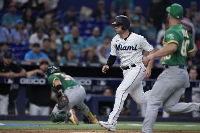 Nick Fortes (centro) de los Marlins de Miami anota una carrera ante los Atléticos de Oakland, el domingo 4 de junio de 2023, en Miami. (AP Foto/Wilfredo Lee)