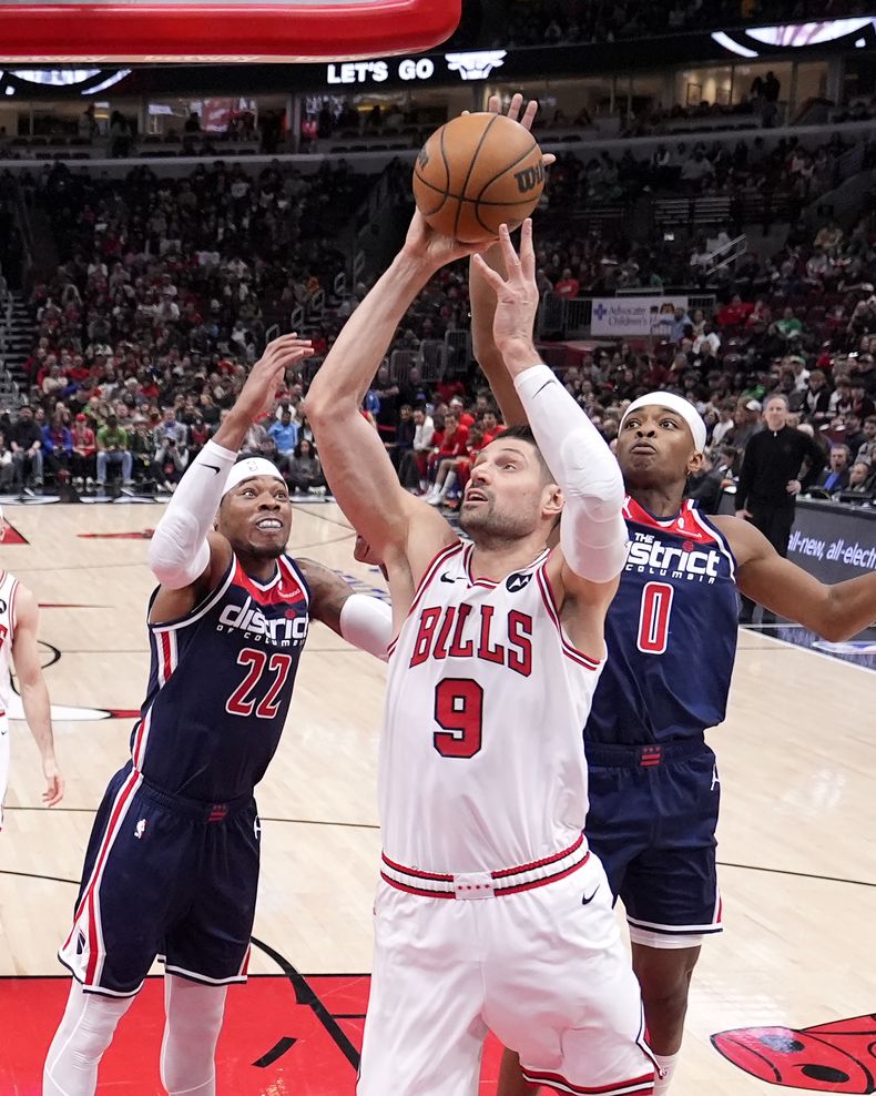 Nikola Vucevic de los Bulls de Chicago avanza hacia la canasta con el balón frente a Richaun Holmes y Bilal Coulibaly de los Wizards de Washington en el encuentro de la NBA del sábado 16 de marzo del 2024. (AP Foto/Charles Rex Arbogast)