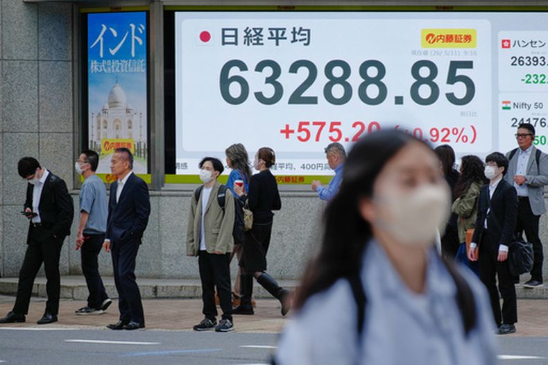 Gente de pie ante una pantalla que muestra el índice bursátil japonés Nikkei en una firma financiera, el lunes 11 de mayo de 2026 en Tokio. (AP Foto/Eugene Hoshiko)