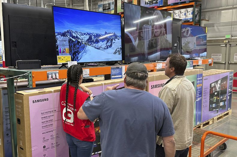 Una pareja de clientes analizan un televisor de gran tamaño con la ayuda de un socio de ventas en un almacén de Costco el jueves 1 de mayo de 2025, en Sheridan, Colorado. (AP Foto/David Zalubowski)