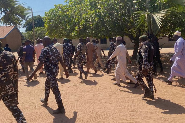 Policías y funcionarios gubernamentales caminan frente a la Escuela Primaria y Secundaria Católica St. Mary, donde hombres armados secuestraron el viernes a menores y miembros del personal en la comunidad de Papiri, Nigeria, el martes 25 de noviembre de 2025. (AP Foto/Yunusa Umar )