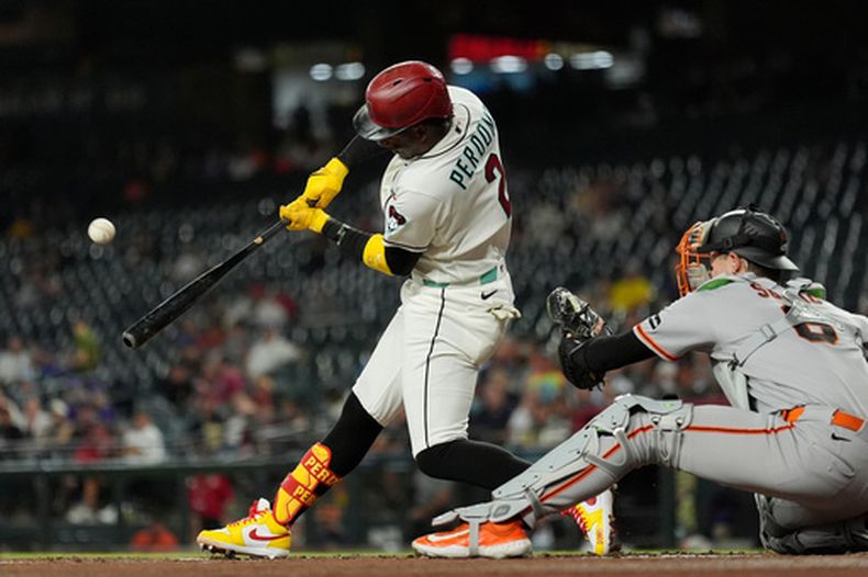 Geraldo Perdomo (2), de los Diamondbacks de Arizona, conecta un elevado de sacrificio productor de dos carreras, mientras Daniel Susac (6), receptor de los Gigantes de San Francisco, se queda esperando durante la primera entrada del juego de béisbol de Grandes Ligas, el miércoles 20 de mayo de 2026, en Phoenix. (AP Foto/Ross D. Franklin)