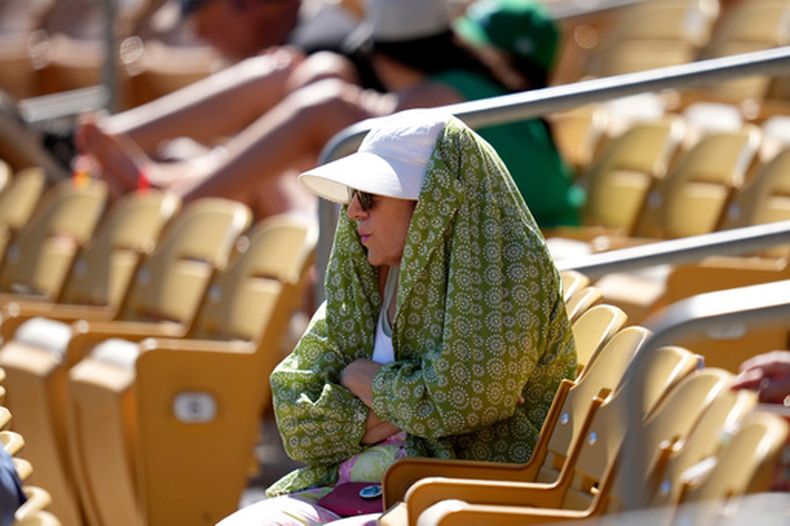 Una aficionada al béisbol se protege del sol durante la cuarta entrada de un partido de entrenamiento de primavera entre los Medias Blancas de Chicago y los Atléticos, el martes 17 de marzo de 2026, en Phoenix. (AP Foto/Ross D. Franklin)