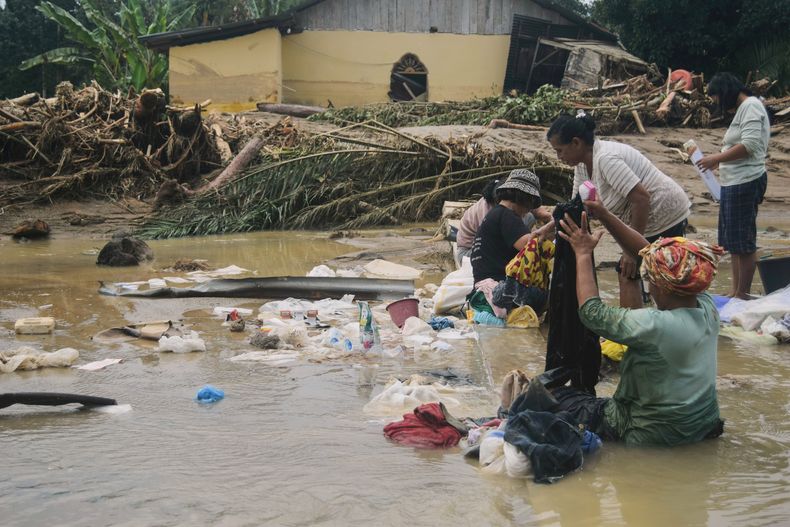Gente utiliza agua de una zona inundada para quitar barro de la ropa en un pueblo afectado por una inundación repentina en Batang Toru, Sumatra del Norte, Indonesia, el sábado 29 de noviembre de 2025. (AP Foto)
