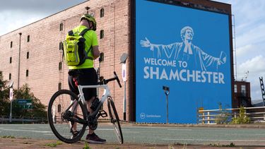 Un apersona toma una foto del anuncio en la calle en referencia al escándalo con el Manchester City el jueves 1 de octubre del 2026. (AP Foto/Jon Super)