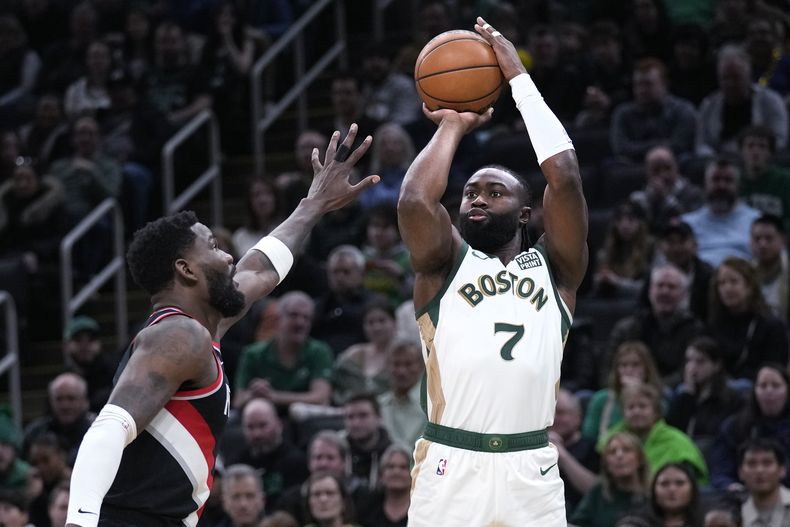 Jaylen Brown (7), de los Celtics de Boston, toma un tiro sobre Deandre Ayton, izquierda, de los Trail Blazers de Portland, durante la primera mitad del juego de baloncesto de la la NBA, el domingo 7 de abril de 2024, en Boston. (AP Foto/Charles Krupa)