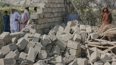 Residentes, junto a la pared derrumbada de una casa dañada en un ataque en la localidad de Patan, en la provincia de Kunar, en el este de Afganistán, el 21 de septiembre de 2026. (AP Foto/Shafiullah Kakar)