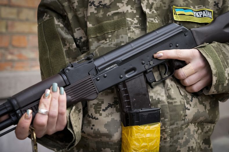 ARCHIVO - Una mujer armada de la defensa civil sostiene un rifle de asalto Kalashnikov mientras patrulla una calle vacía debido a un toque de queda en Kyiv, Ucrania, 27 de febrero de 2022. Estados Unidos ha transferido a Ucrania 1,1 millones de cartuchos de munición para armas ligeras que incautó a Irán, informó el miércoles el Mando Central estadounidense. (AP Foto/Efrem Lukatsky, File)