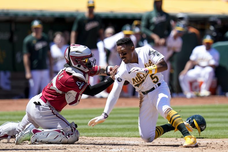 José Herrera, izquierda, receptor de Diamondbacks de Arizona, pone fuera a Tony Kemp, de los Atléticos de Oakland, en el plato durante la séptima entrada en el juego de béisbol en Oakland, California, el miércoles 17 de mayo de 2023. (AP Foto/Godofredo A. Vásquez)