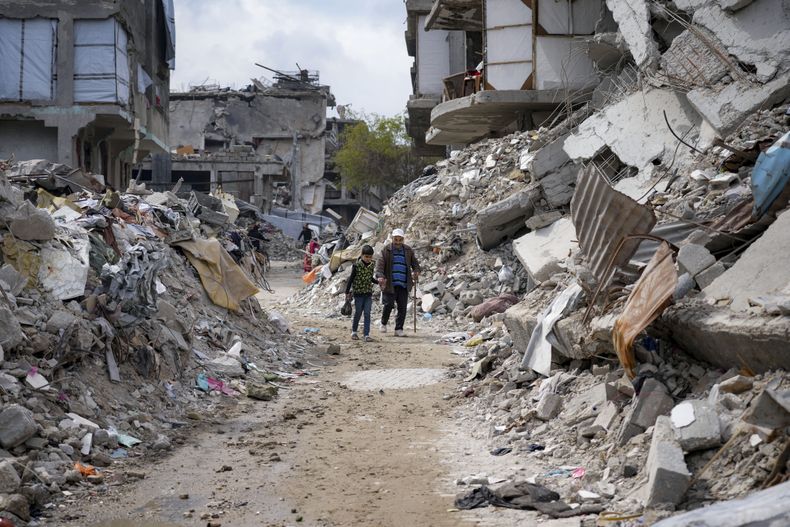 Dos personas caminan entre los escombros de viviendas destruidas por la ofensiva del ejército israelí contra Hamás, el miércoles 19 de febrero de 2025, en Jabaliya, en el norte de la Franja de Gaza. (AP Foto/Abdel Kareem Hana)