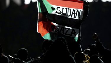 Un individuo alza una bandera que menciona a Sudán y Gaza durante el descanso del Super Bowl, el domingo 9 de febrero de 2025, en Nueva Orleans. (AP Foto/Matt Slocum)