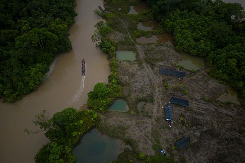 ARCHIVO – Un bote, con gasolina que será transportada para alimentar maquinaria para la minería ilegal, maniobra frente a un área que fue objeto de minería y después reforestada por la Asociación Nuestra Casa Común, cerca de Paimado, Colombia, el 24 de septiembre de 2024. (AP Foto/Ivan Valencia, Archivo)