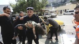 Un policía de Hamas llega con una niña herida a un hospital el domingo 8 de octubre de 2023, en Beit Lahiya, en la Franja de Gaza. (AP Foto/Mahmoud Essa)